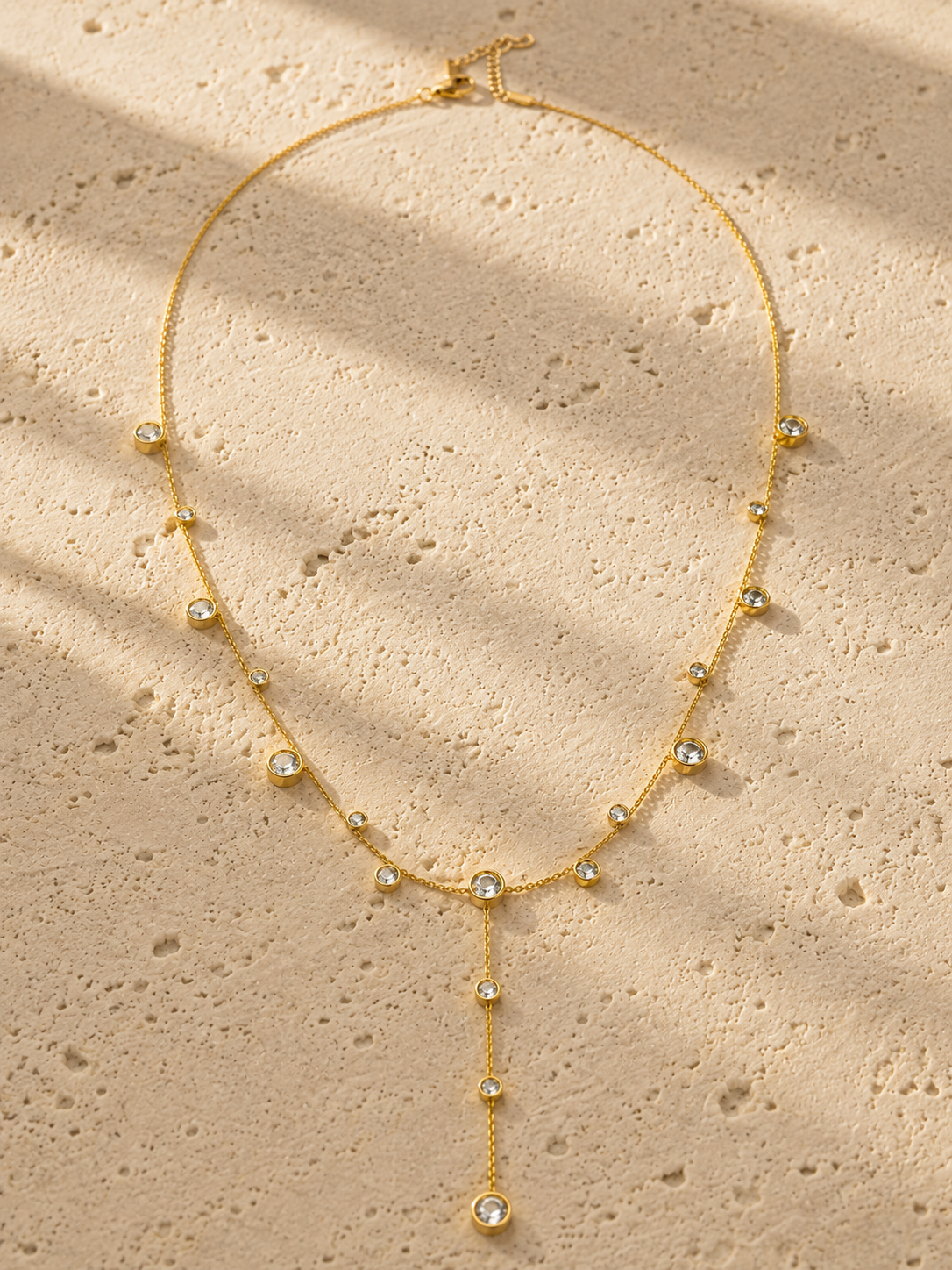 Minimalist bezel CZ Y-drop necklace in gold flat lay product photography