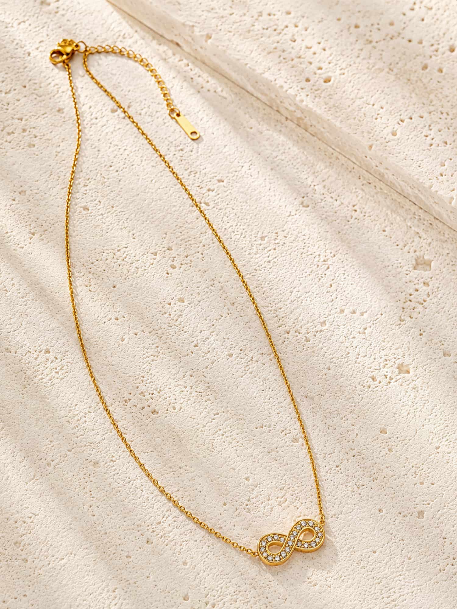 Infinity CZ pendant necklace displayed on a textured stone surface with a delicate gold chain.