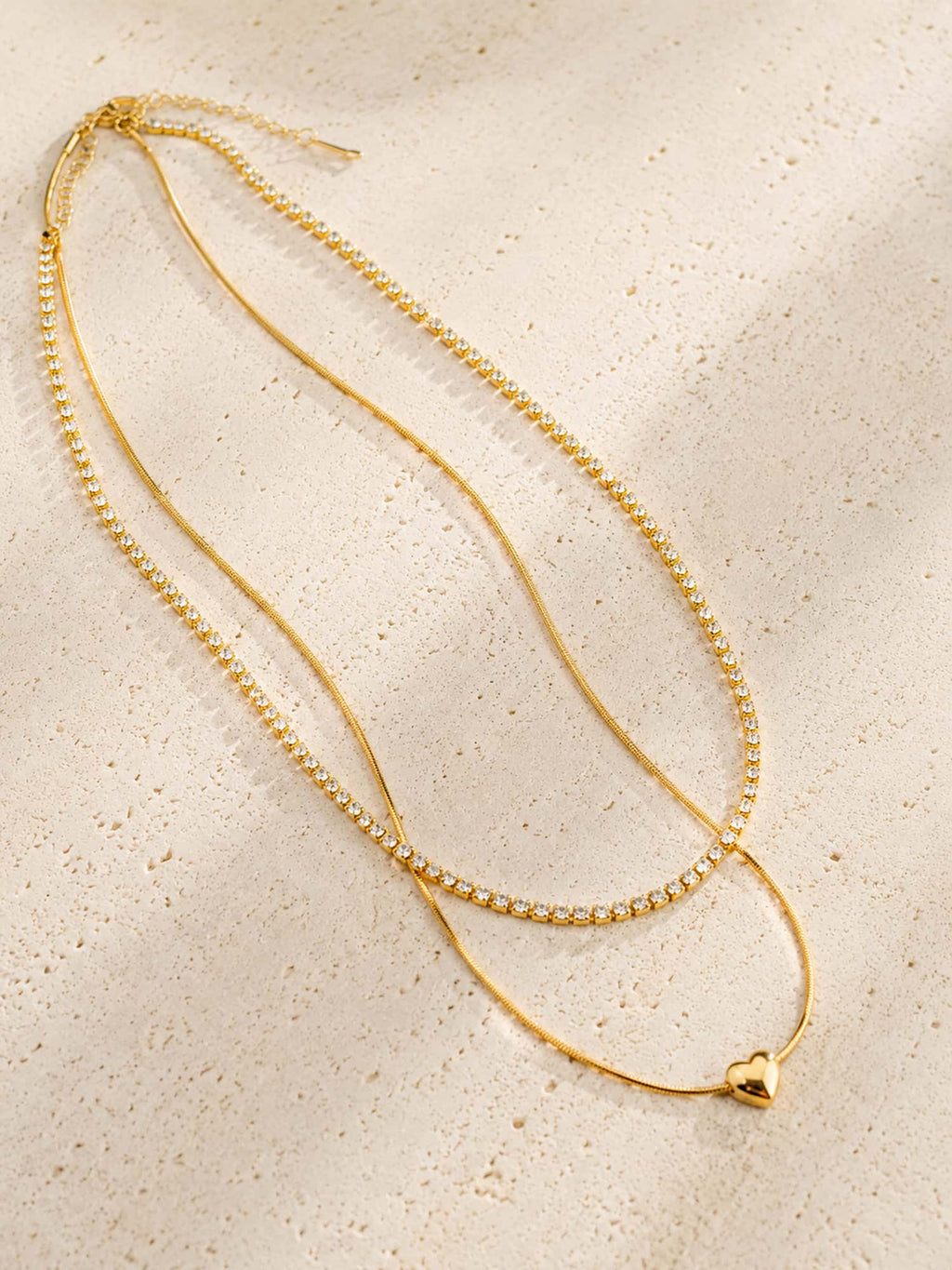 Double-layer heart and CZ tennis necklace displayed on a textured stone surface showcasing its elegant layered design.