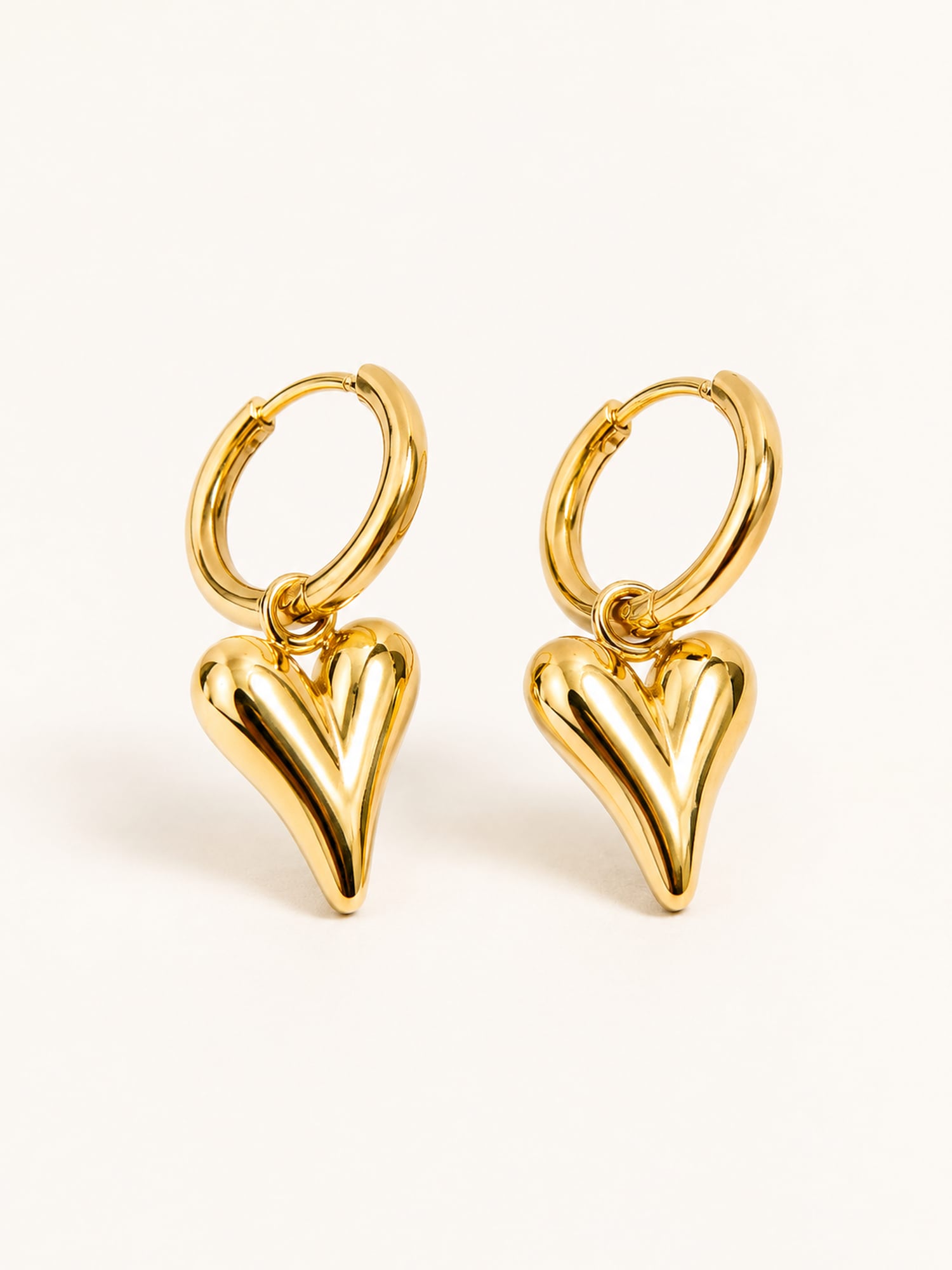 Puffy heart huggie earrings in polished gold with a modern minimalist drop design.